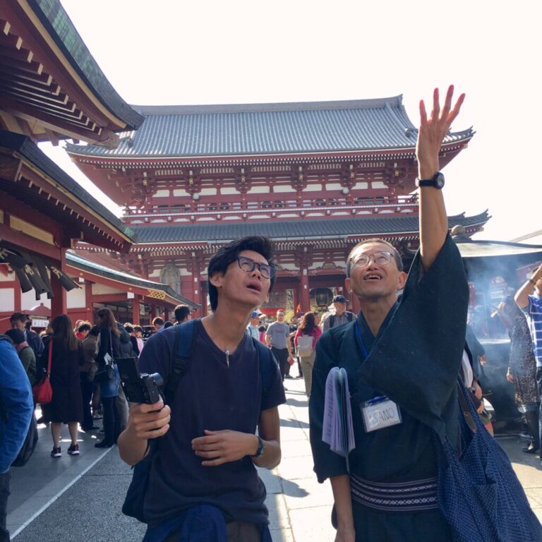 A guide from 'Tokyo Free Walking Tour,' wearing a kimono, is pointing over there at asakusa sensoji temple.