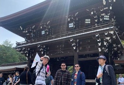 A guide from "Tokyo Free Walking Tour" is pointing over there at Meiji Shrine in Tokyo.