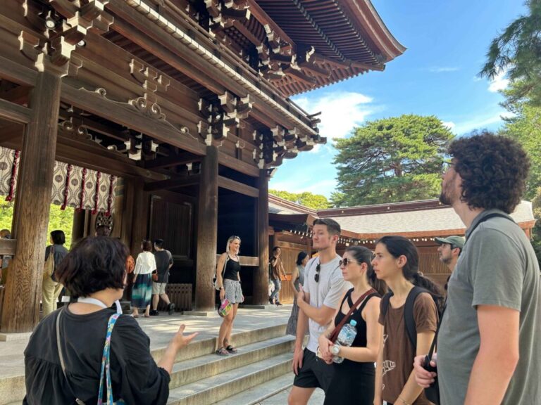 A guide is explaining the gate of Meiji Shrine in Tokyo to a small group of four guests.