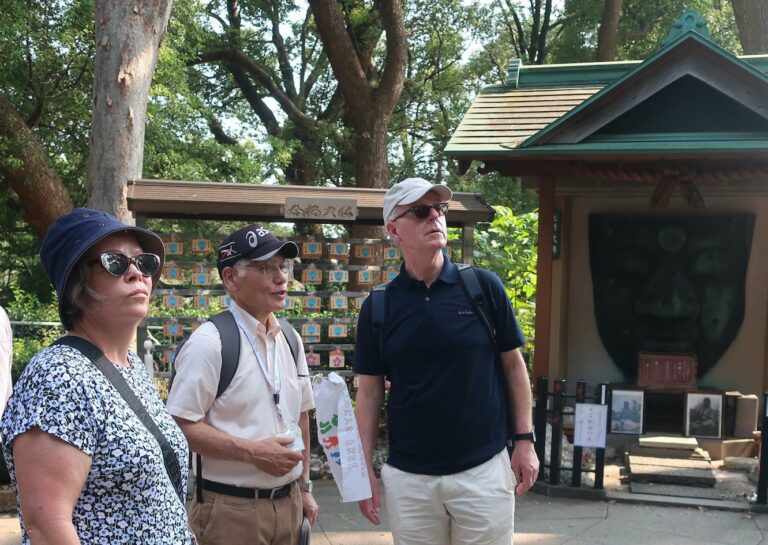 Two guests and a guide from 'Tokyo Free Walking Tour' are looking at something.